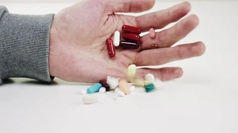 Many pills fall from the hand of a man. Pharmacy Stock Footage 100042755