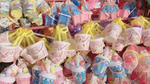 Many plastic buckets and spades for sale at the seaside. The toys are bright Video stock 129694232