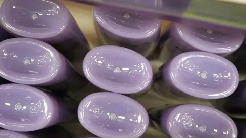 Many plastic jars with purple shampoo or shower gel in a row. Top view. Stock Footage 309698700