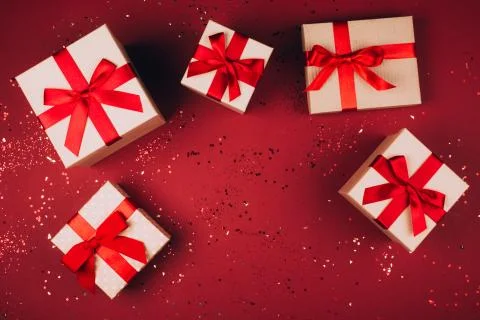 Many present boxes with red bow on red background Foto stock