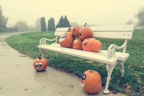 Many pumpinks with painted faces on white porch. Stock Photos