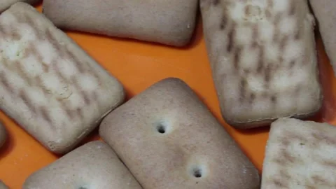 Many rectangular biscuits with small pores in red plate Stock Footage 145843572