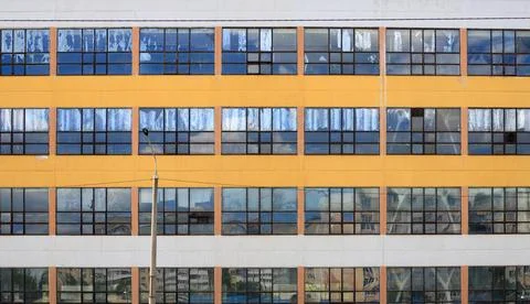 Many rectangular window frames reflecting blue sky on a huge warehouse struct Stock Photos