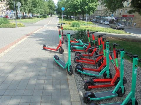 Many red and green shared electric scooters on sunny street. Foto stock