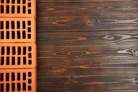Many red bricks on wooden table, flat lay with space for text. Building mat.. Stock Photos