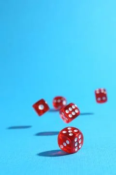 Many red game dices falling on light blue background. Space for text Stock Photos