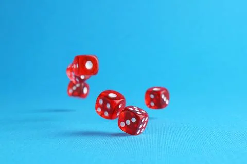 Many red game dices falling on light blue background. Space for text Stock Photos