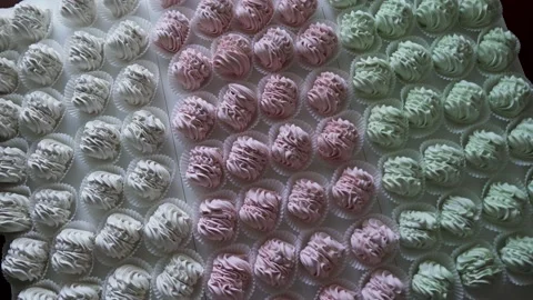 Many red, green and white cooked marshmallows lie on the table. Camera rotating Stock Footage 215891408