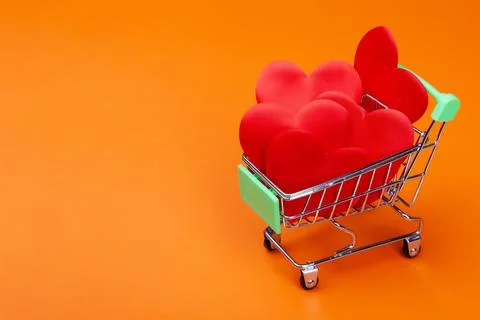 Many red hearts inside mini grocery cart on colored background Foto stock