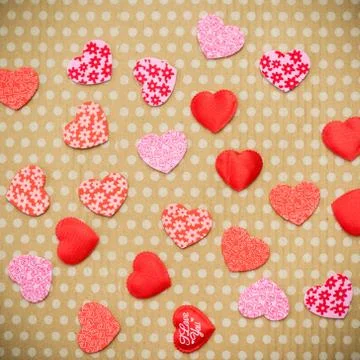 Many red hearts lie on an old cardboard background in white peas. Foto stock