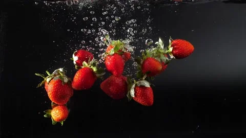 Many red strawberries fall into the water with splashes, slowly sinking to the b Stock Footage 133340779