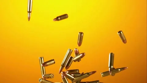 Many rifle bullets falling against an orange gradient background in slow motion Stock Footage 326625117
