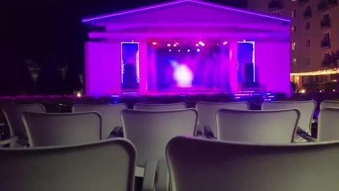 Many rows of chairs against the backdrop of colorful lights on the stage at Stock-Footage 295603887