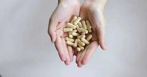 Many the same brown pills in woman's hands on white background, closeup view. Stock Footage 145446373