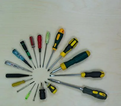 Many screwdrivers from small to large, on a light wooden background. Stock Photos