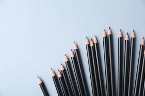 Many sharp graphite pencils on light grey background, flat lay. Space for tex 库存照片