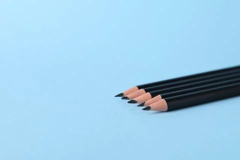 Many sharp graphite pencils on light blue background, closeup. Space for text Stock Photos