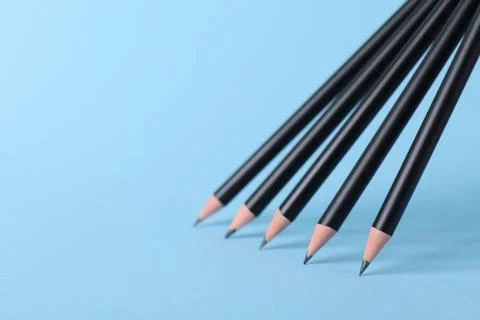Many sharp graphite pencils on light blue background, closeup. Space for text 스톡 사진