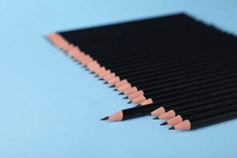 Many sharp graphite pencils on light blue background, closeup Foto stock