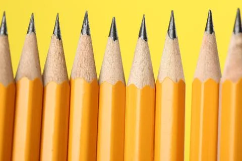 Many sharp graphite pencils on yellow background, macro view Stock Photos
