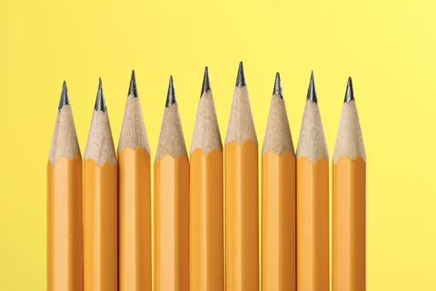 Many sharp graphite pencils on yellow background, macro view Stock Photos