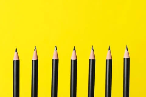 Many sharp graphite pencils on yellow background, closeup. Space for text Foto stock