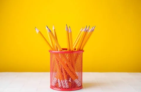 Many sharp pencils in holder on light table against yellow background Stock Photos