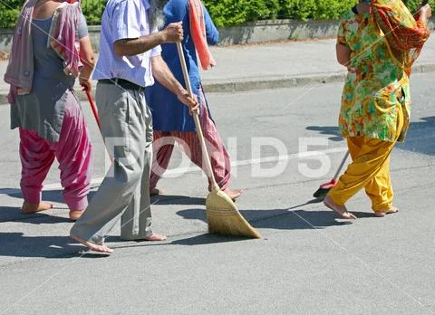 Many Sikh people while sweeping the street during the religious ceremony Stock Photos
