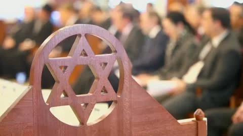 Many sit in synagogue behind wooden merkaba symbol at memorial Stock Footage