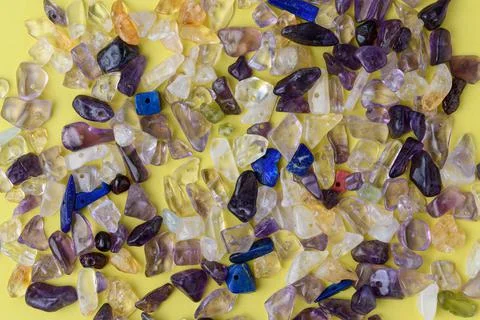 Many small and multi-colored natural stones on a yellow background Stock Photos