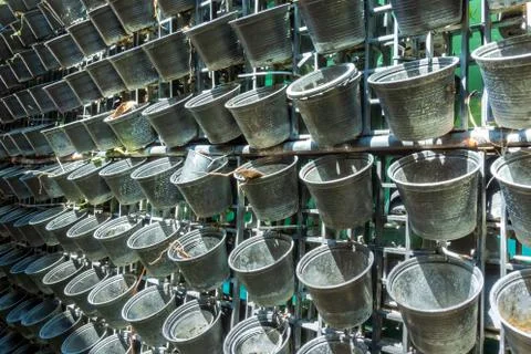 Many small, empty black plastic pots were hung on a metal fence in the garden Stock Photos