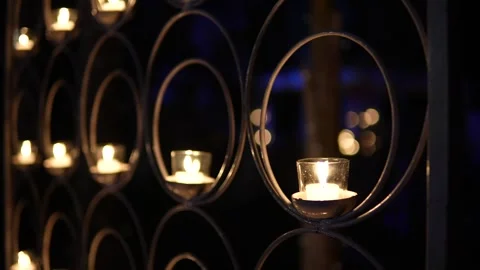 Many small glowing candles inside a decorative metal wall display Stock Footage 335270761