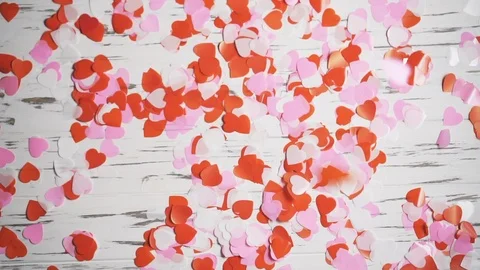 Many small multi-colored hearts fall on the surface of the table, slow motion. Stock Footage 122859101