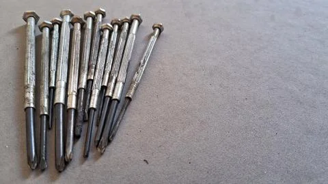 Many small precision screwdrivers arranged neatly on a grey surface Stock Photos