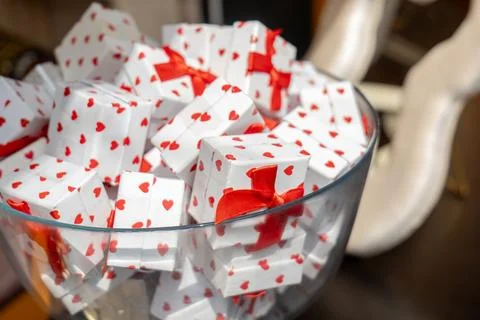 Many small white gift boxes with red heart pattern and red ribbon bows piled Stock Photos