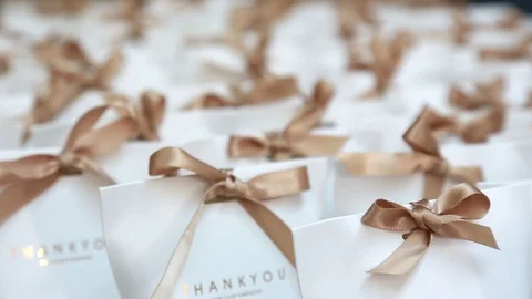Many small white paper gift boxes with ribbon bows on the table. Video stock 109435629