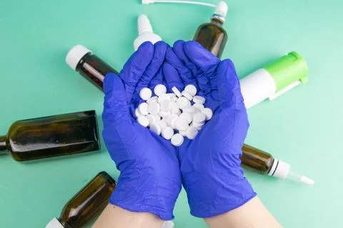 Many small white pill in the doctor's hands dressed in the medical blue dispo Stock Photos