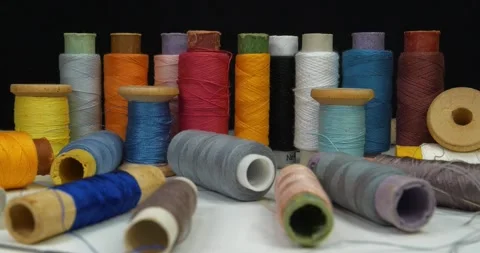 Many spools with multi-colored threads rotates on dark background Stock Footage 310557983