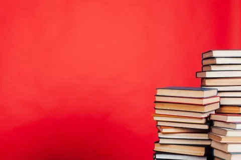 Many stacks of educational books to study in the college library on a red Foto stock