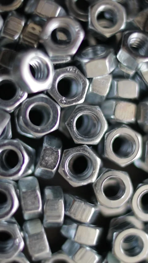 Many stainless hex nuts rotating close-up. Metal industry concept. Vertical Stock Footage 271244240