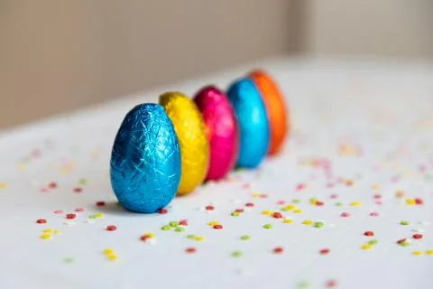 Many standing colored chocolate easter eggs on white background and colorful  Foto stock