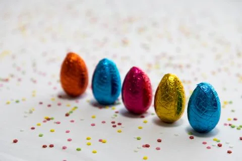 Many standing colored chocolate easter eggs on white background and colorful  Stock Photos