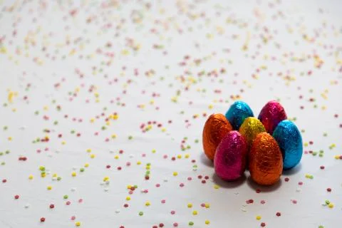 Many standing colored chocolate easter eggs on white background and colorful  Stock Photos