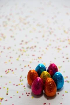 Many standing colored chocolate easter eggs on white background and colorful  Foto stock
