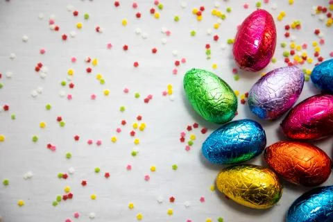 Many standing colored chocolate easter eggs on white background and colorful  Stock Photos