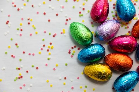 Many standing colored chocolate easter eggs on white background and colorful  Stock Photos