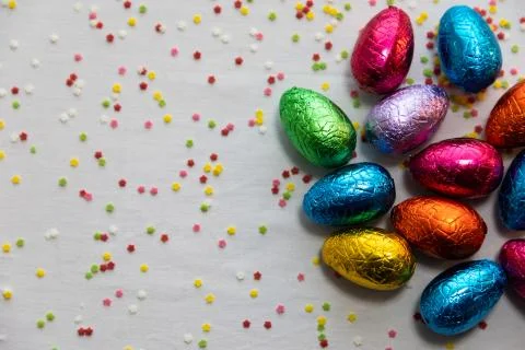 Many standing colored chocolate easter eggs on white background and colorful  Stock Photos