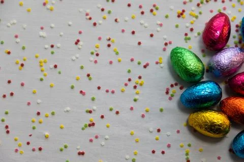 Many standing colored chocolate easter eggs on white background and colorful  Stock Photos