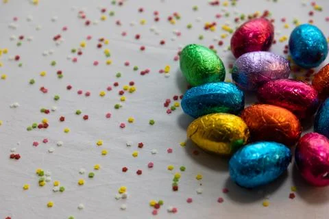 Many standing colored chocolate easter eggs on white background and colorful  Foto stock