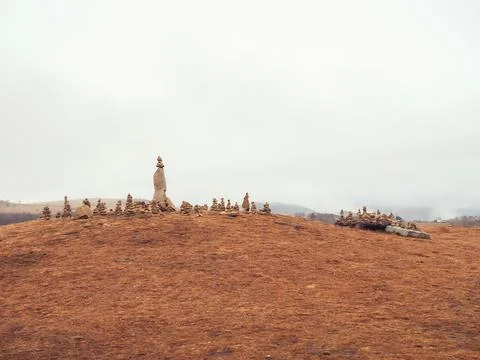 Many stone pyramids are built on top of the mountain covered with dry grass Stock Photos